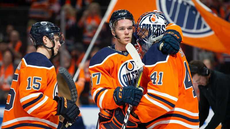 Konors Makdeivids (centrā) apsveicot vārtsargu Maiku Smitu viņa pirmajā uzvarā Edmontonas "Oilers" kreklā. Foto: Codie McLachlan/AFP/Scanpix