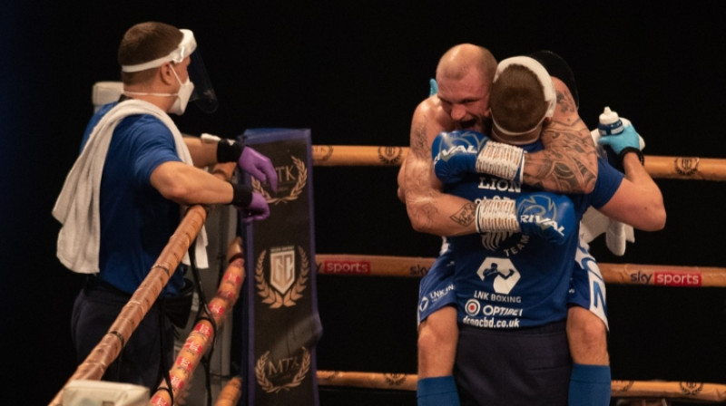 Ričards Bolotņiks pēc cīņas pret Seržu Mišelu metas sava trenera Dmitrija Šiholaja apskāvienos. Foto: MTK Global